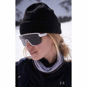 Person wearing Smith Optics white frame sunglasses and a black beanie in a snowy environment