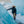 Person in a black parka and tan pants standing between blue glacier walls