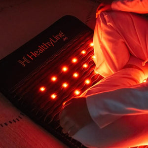 Person sitting next to a HealthyLine Jet red light therapy mat