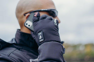 Person wearing black heated gloves while talking on a mobile phone