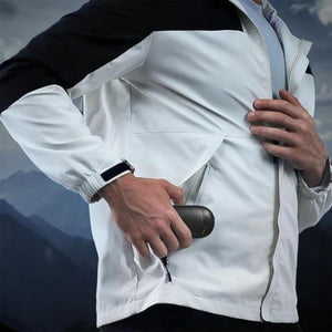 Person placing an ActionHeat battery pack into the pocket of a white and black jacket