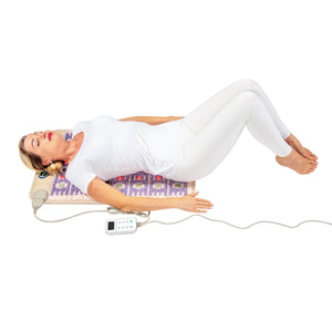 Woman lying on an infrared therapy mat with a digital controller
