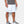 Under Armour white athletic shorts on a person wearing a grey t-shirt and grey sneakers
