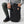 Person placing a black water bottle into the side pocket of a black Fjallraven backpack