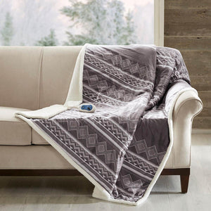 Woolrich grey geometric pattern heated throw blanket with white sherpa lining on a beige sofa