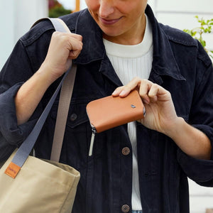 Person holding a tan Bellroy leather zip wallet