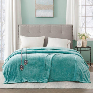 Teal heated blanket with two controllers draped over a bed