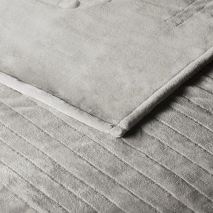 Close up of grey velvet textured blanket with horizontal channel stitching