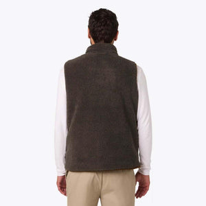 Back view of a man wearing a brown Mobile Warming fleece vest over a white long sleeve shirt