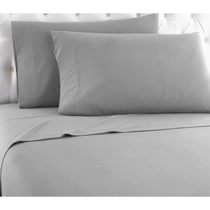 Grey bed sheet set with two matching pillowcases on a white tufted headboard