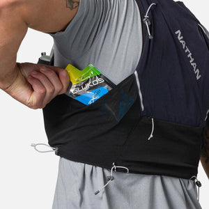 Runner placing a Glukos energy gel into the mesh pocket of a Nathan hydration vest