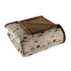 Shavel folded throw blanket with brown sherpa lining and camping themed print on tan fabric