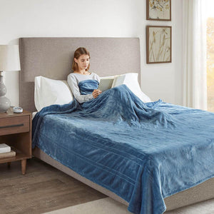 Person reading a book in bed under a blue Beautyrest heated blanket