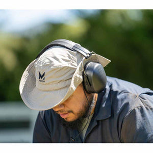 Person wearing a beige bucket hat and black protective earmuffs
