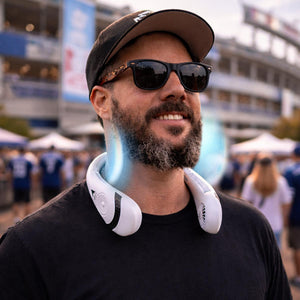 Man wearing a white portable neck fan at an outdoor stadium