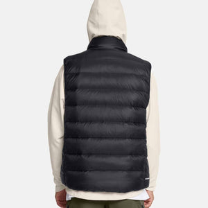Back view of Under Armour black quilted puffer vest worn over a beige hooded sweatshirt