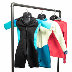 Three wetsuits hanging on a metal rack